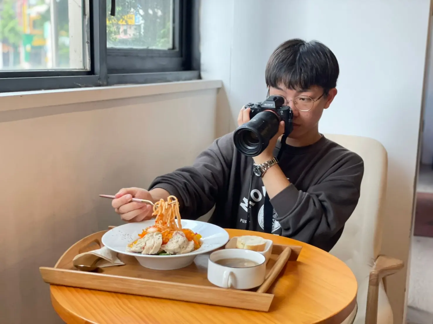 Derrick 拿著相機拍攝桌上的餐點