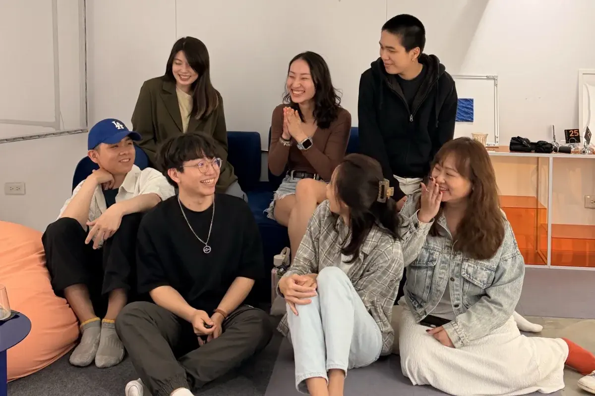 Derrick 和幾位創作者朋友在聚會上圍坐聊天，大家笑得很開心